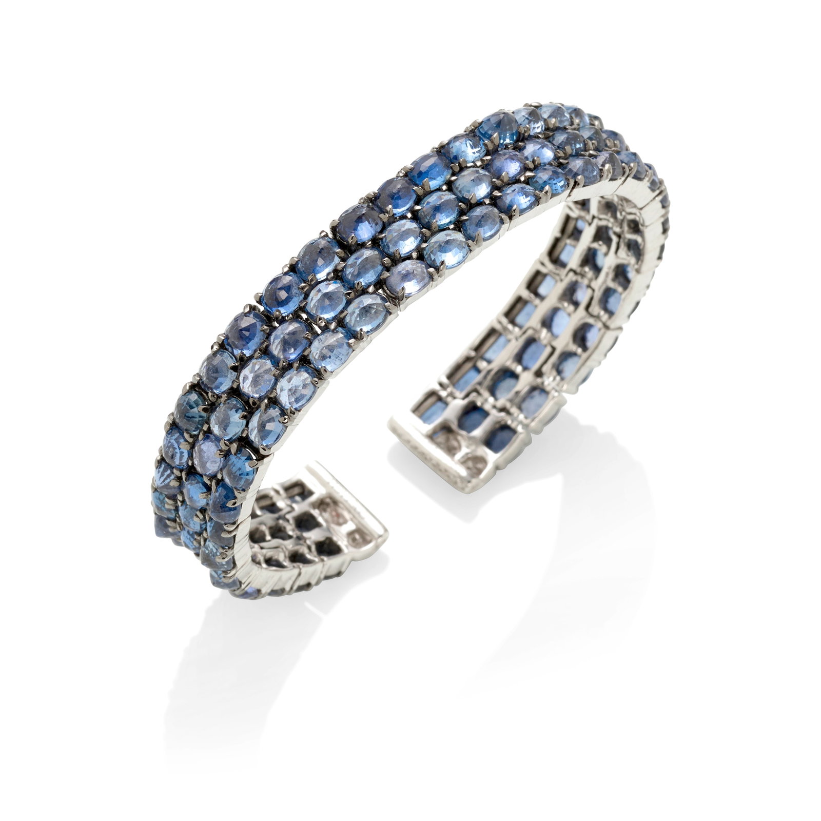 COSTAGLI: AN 18K WHITE GOLD SAPPHIRE AND DIAMOND BRACELET: COSTAGLI: AN 18K WHITE GOLD SAPPHIRE AND DIAMOND BRACELET A flexible cuff, comprising three rows of oval-shaped sapphires set pavilion up, accented with round brilliant-cut diamonds; signed Costagli