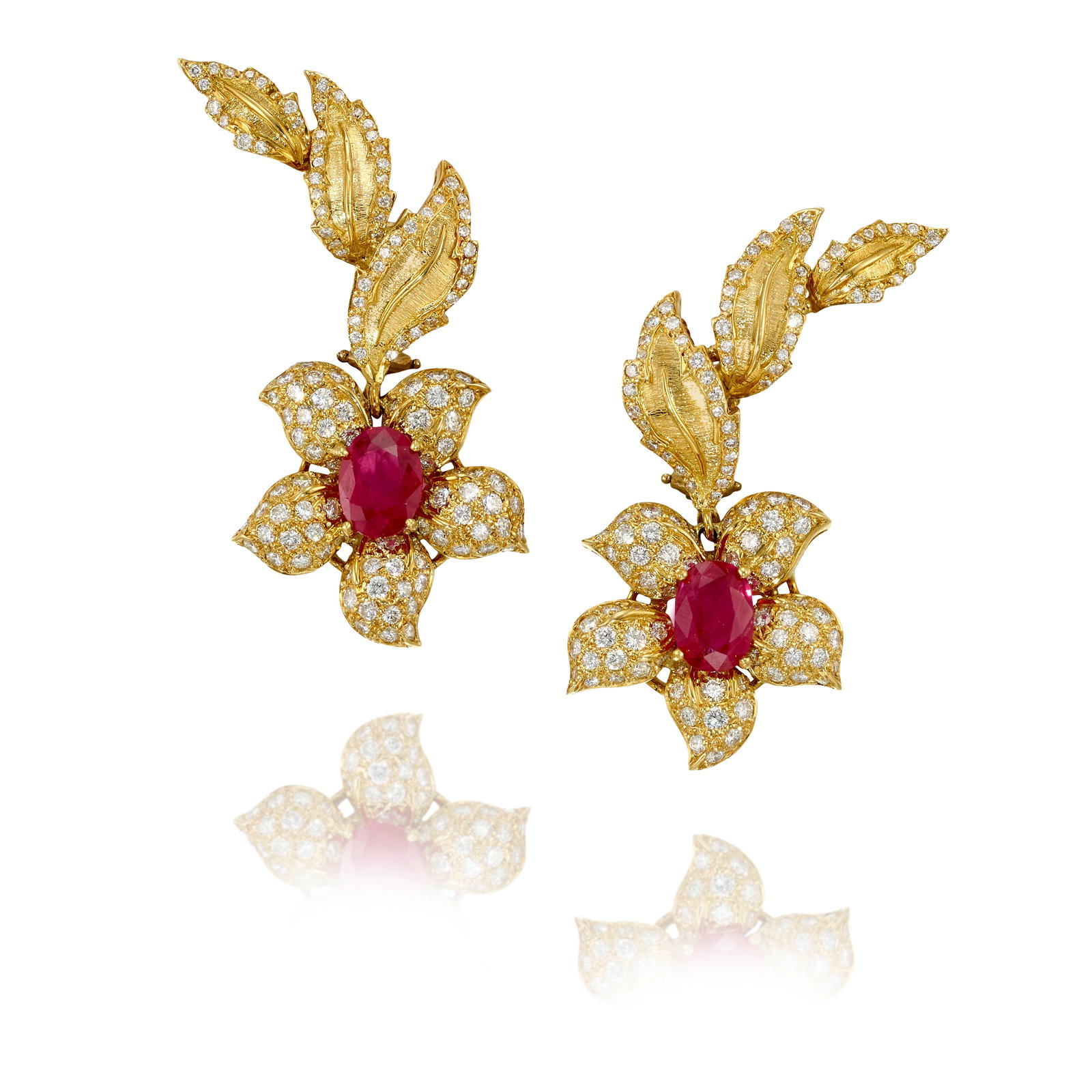 A PAIR OF RUBY AND DIAMOND EARRINGS: A PAIR OF RUBY AND DIAMOND EARRINGS Each of foliate design, with flower pendants centering oval-shaped rubies, accented with round brilliant-cut diamonds; estimated total ruby weight 3.20 carats; esti