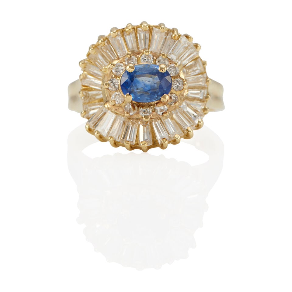 A 14K YELLOW GOLD, SAPPHIRE AND DIAMOND RING: A 14K YELLOW GOLD, SAPPHIRE AND DIAMOND RING • An oval shaped sapphire weighing approximately 0.70 carat • Numerous tapered baguette and round shaped diamonds weighing approximately 0.90