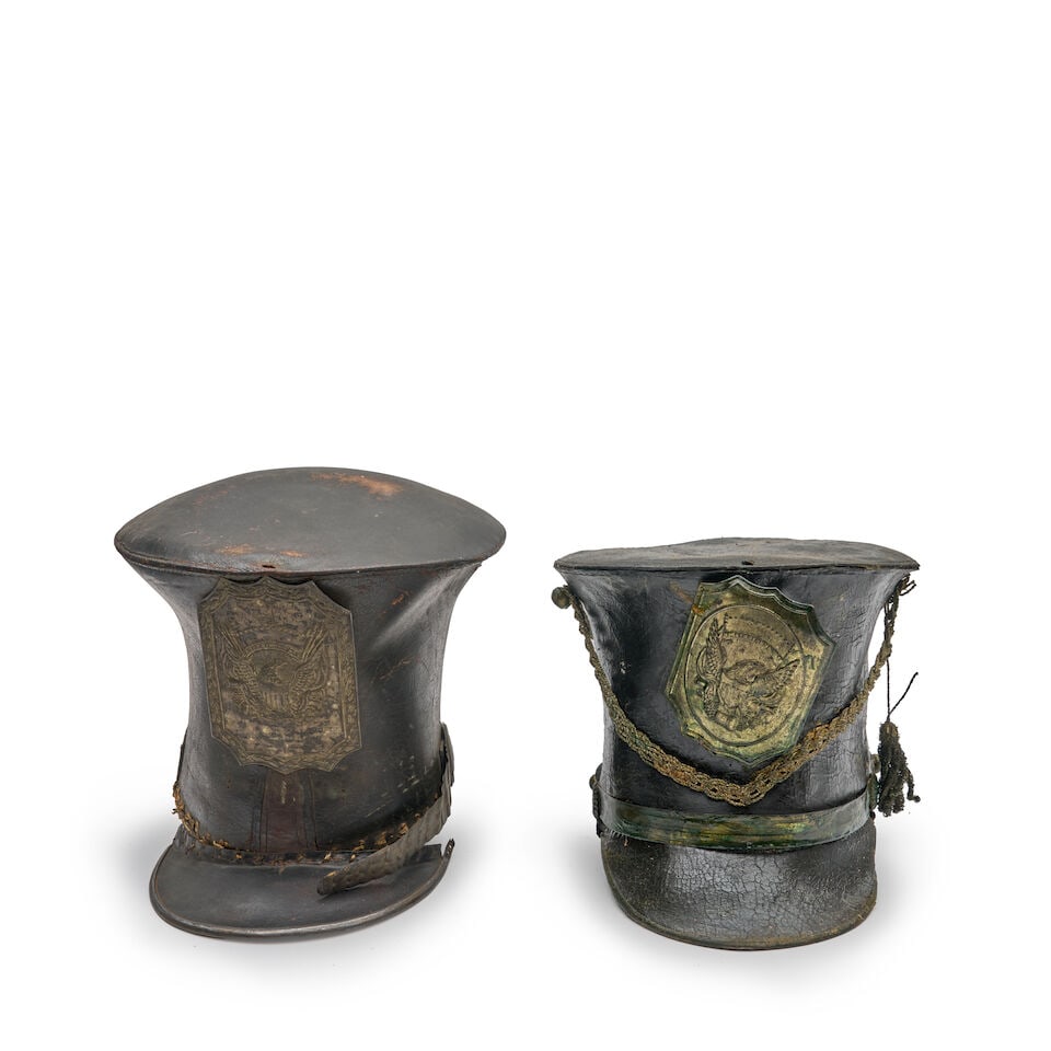 TWO NEW ENGLAND MILITIA BELL CROWNED CAPS,: TWO NEW ENGLAND MILITIA BELL CROWNED CAPS, c. 1810-1820. The incomplete leather caps with embossed eagle plates and leather brims. For further information on this lot please visit Bonhams.com For furt