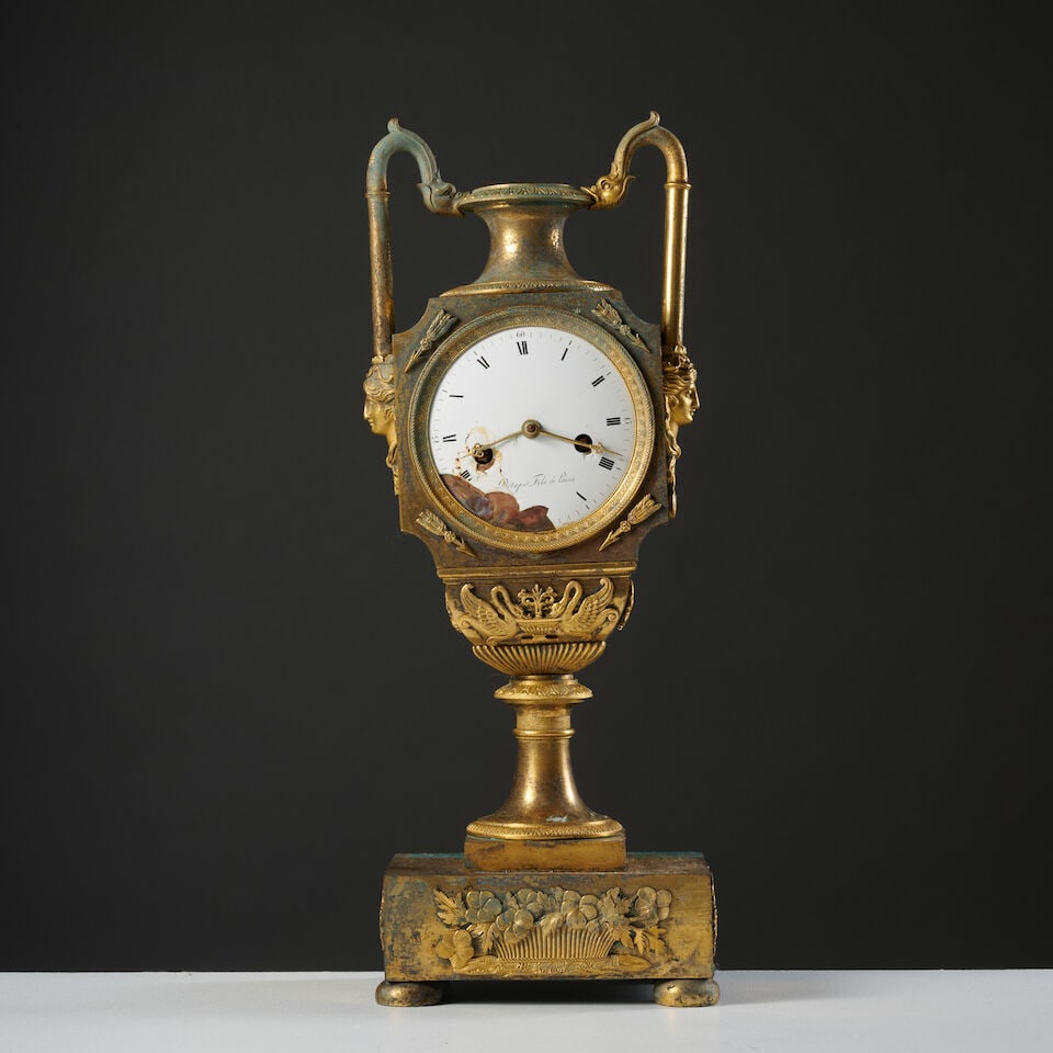 Pendule en bronze doré en forme d'urne d'époque Empire An Empire urn-shaped clock in g...: Pendule en bronze doré en forme d'urne d'époque Empire An Empire urn-shaped clock in gilt-bronze Le cadran émaillé blanc à chiffres romains pour les heures est signé D