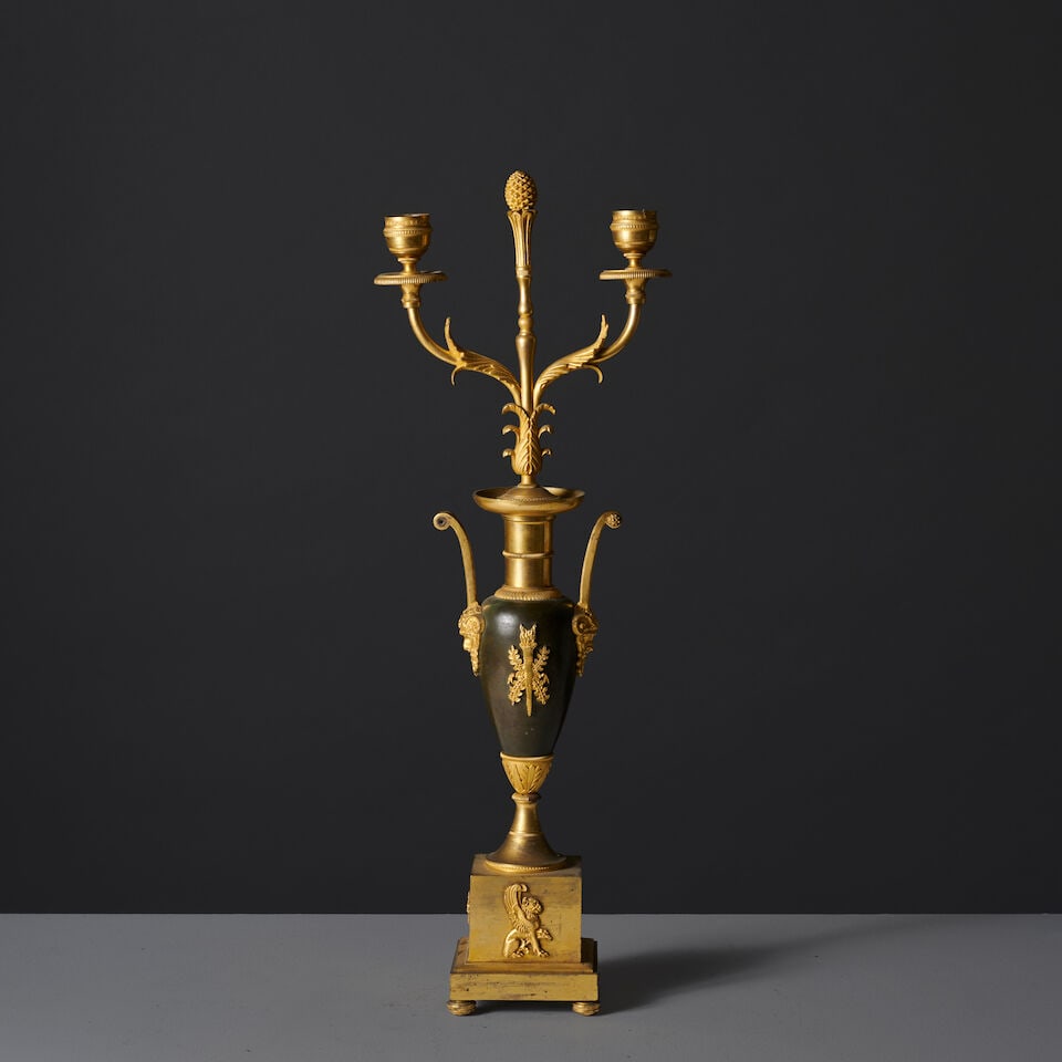 Candélabre à deux bras de lumière en bronze à patine brune et dorée d'&...: Candélabre à deux bras de lumière en bronze à patine brune et dorée d'époque Empire An Empire two-light candelabrum in patinated and gilt-bronze Le vase, de forme fuseau