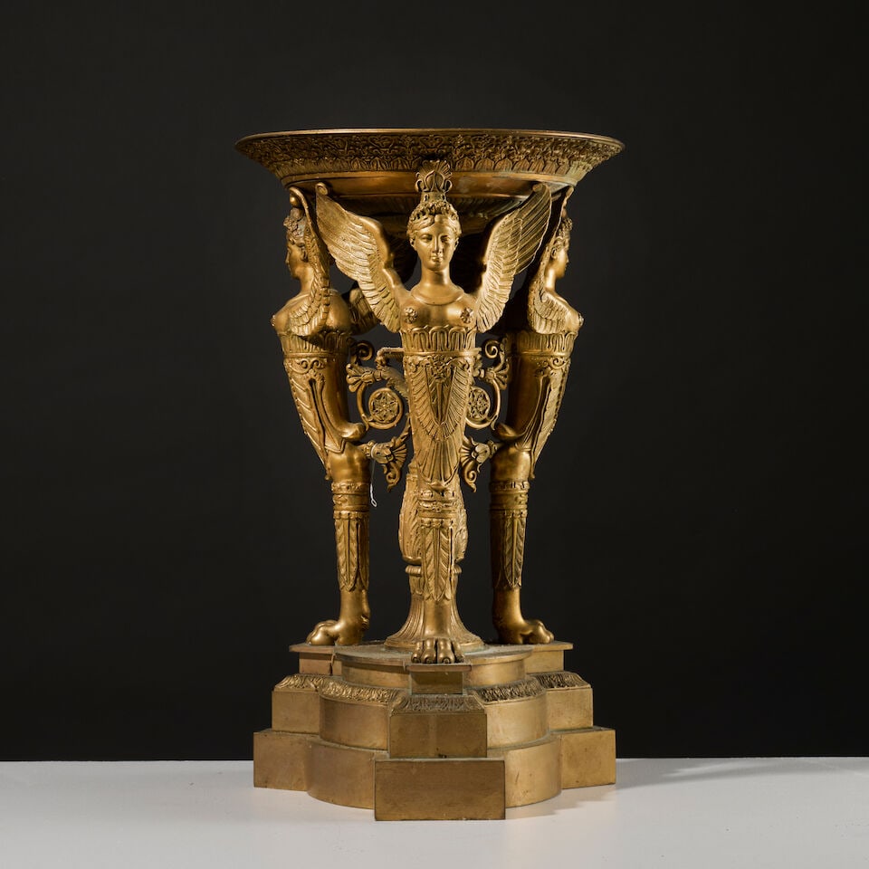 Grande coupe en bronze doré et ciselé supportée par trois sphinges ailés du ...: Grande coupe en bronze doré et ciselé supportée par trois sphinges ailés du XIXe siècle A large XIXe century bowl in gilt-bronze supported by three winged sphinxes La coupe