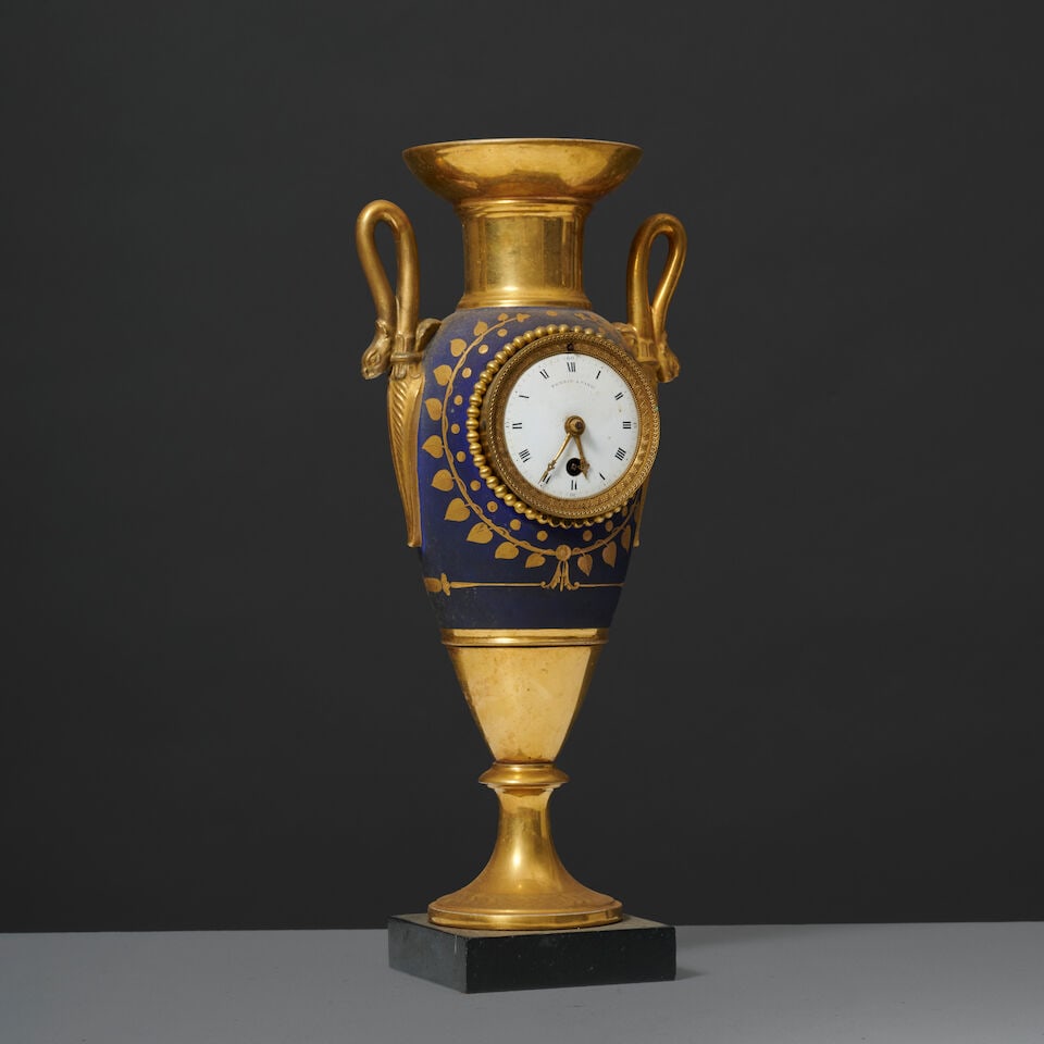 Pendule en forme de vase fuseau en porcelaine de Paris, d'époque Empire A spindle-shaped Pa...: Pendule en forme de vase fuseau en porcelaine de Paris, d'époque Empire A spindle-shaped Paris porcelain vase and clock, early 19th century Le col, piédouche et anses à fond or, la