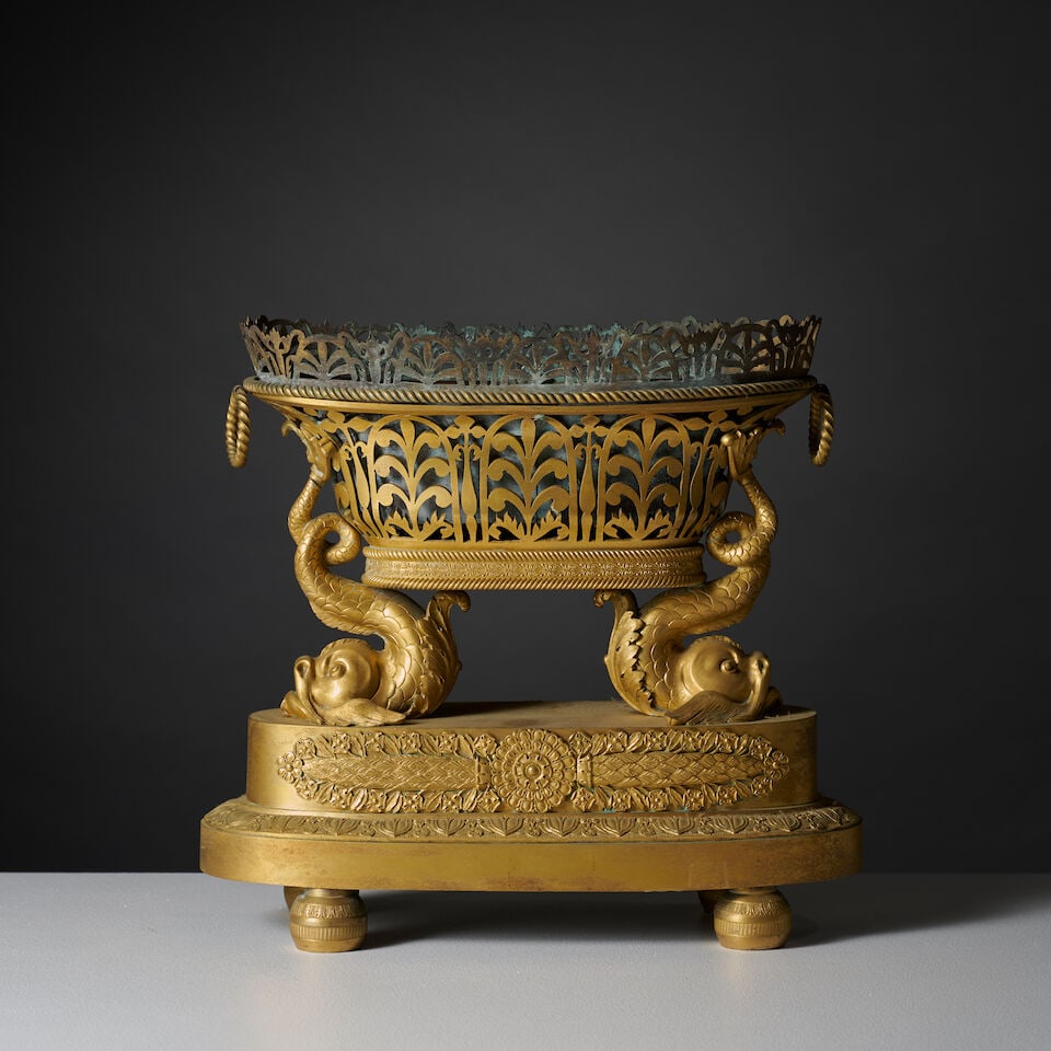 Centre de table de forme ovale à vasque ajourée de palmettes retenue par deux dauphins...: Centre de table de forme ovale à vasque ajourée de palmettes retenue par deux dauphins de la première partie du XIXe siècle An early 19th century oval centerpiece with a pierced