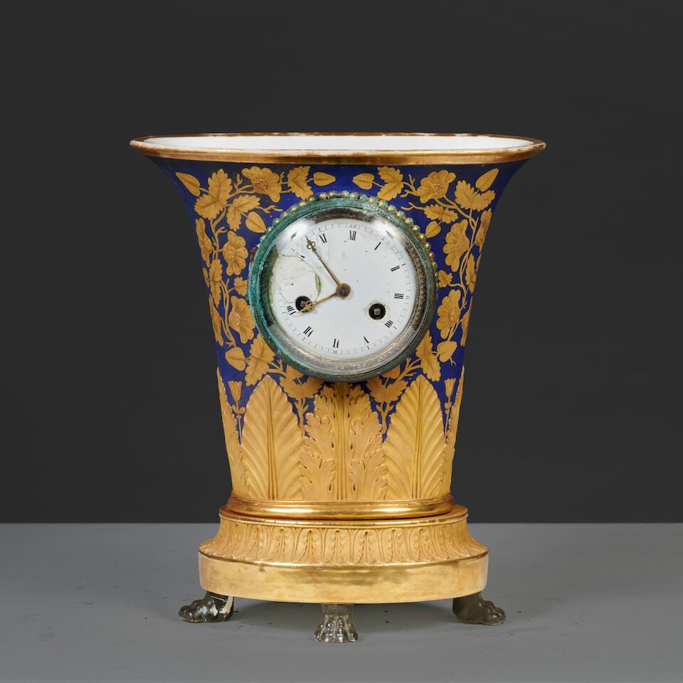 Pendule inscrite dans un vase cornet en porcelaine bleue et or d'époque Empire A clock set ...: Pendule inscrite dans un vase cornet en porcelaine bleue et or d'époque Empire A clock set within a cornucopia-shaped vase in blue and gilt porcelain, first half of the 19th