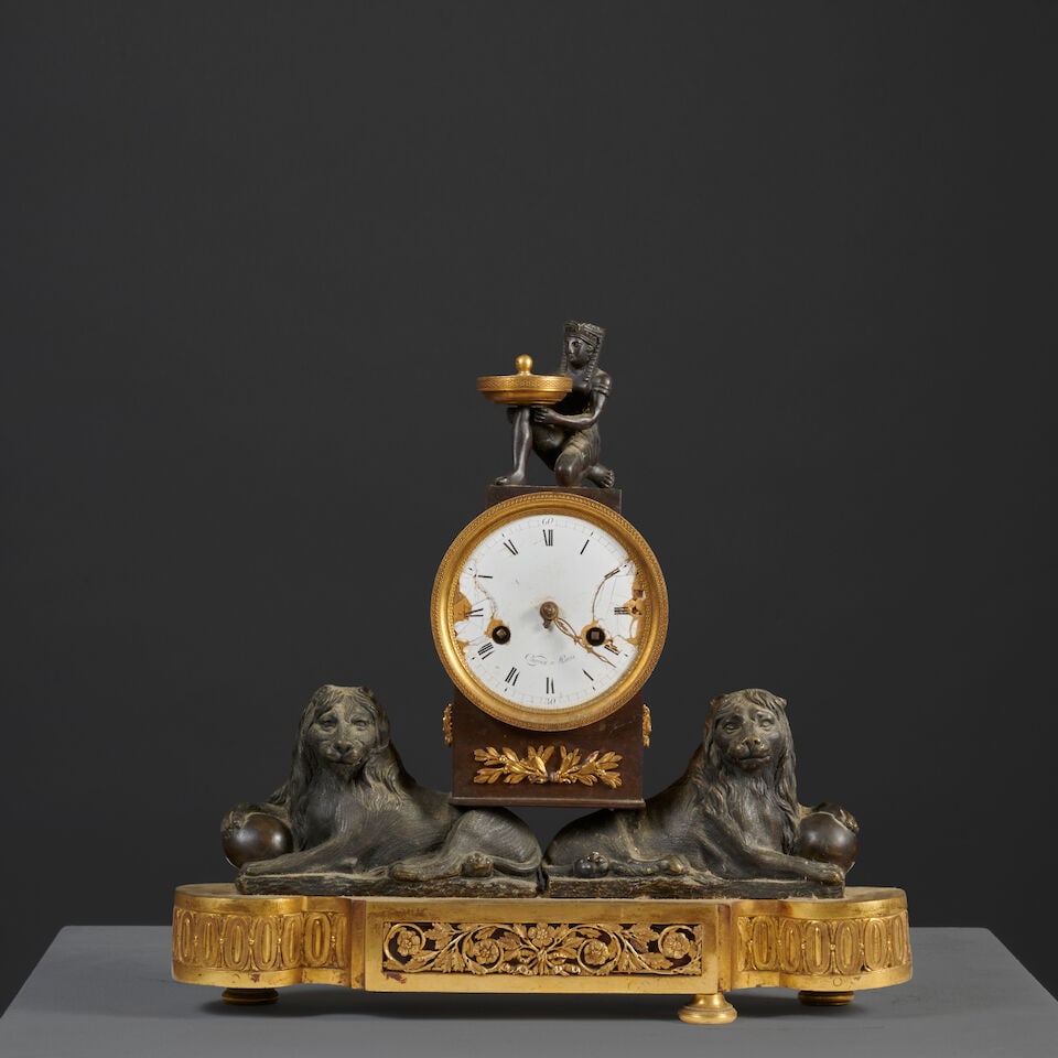 Pendule en bronze doré et patiné à deux lions supportants le mouvement d'épo...: Pendule en bronze doré et patiné à deux lions supportants le mouvement d'époque Empire An Empire gilt and patinated bronze clock with two lions supporting the movement Les deux