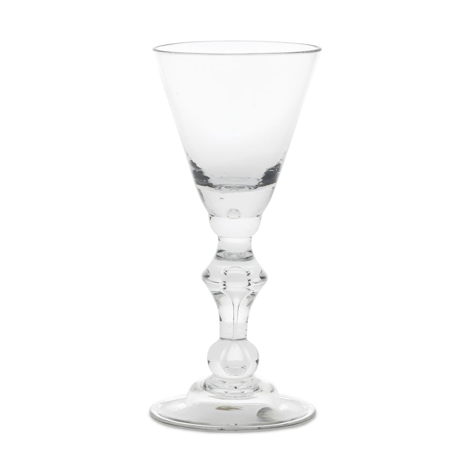A fine baluster wine glass, circa 1710-20: A fine baluster wine glass, circa 1710-20 The round funnel bowl with a solid base containing a small tear, set on a half knop, on a stem with a teared angular knop, the tear extending into a basal kno