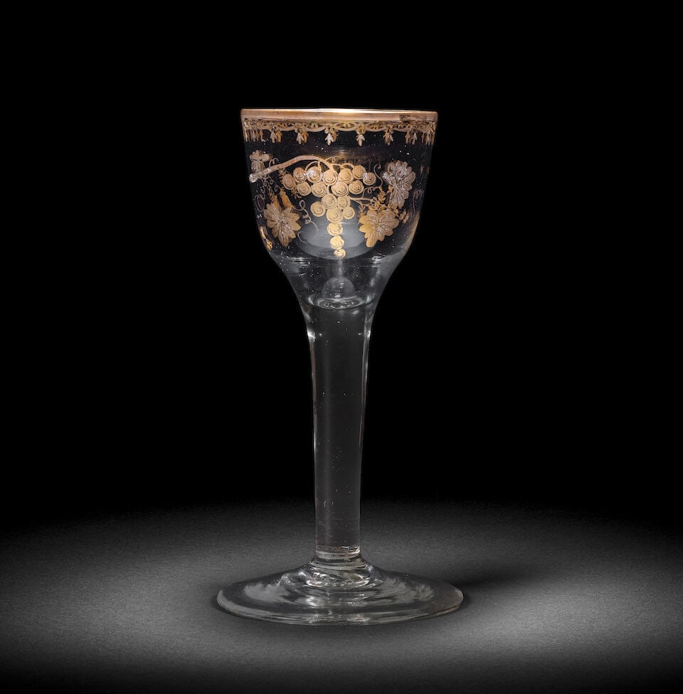 A Giles gilded plain stem wine glass, circa 1765: A Giles gilded plain stem wine glass, circa 1765 Decorated in the London workshop of James Giles, the ogee bowl finely decorated in gilding with a branch of fruiting vine, scattered floral sprigs to