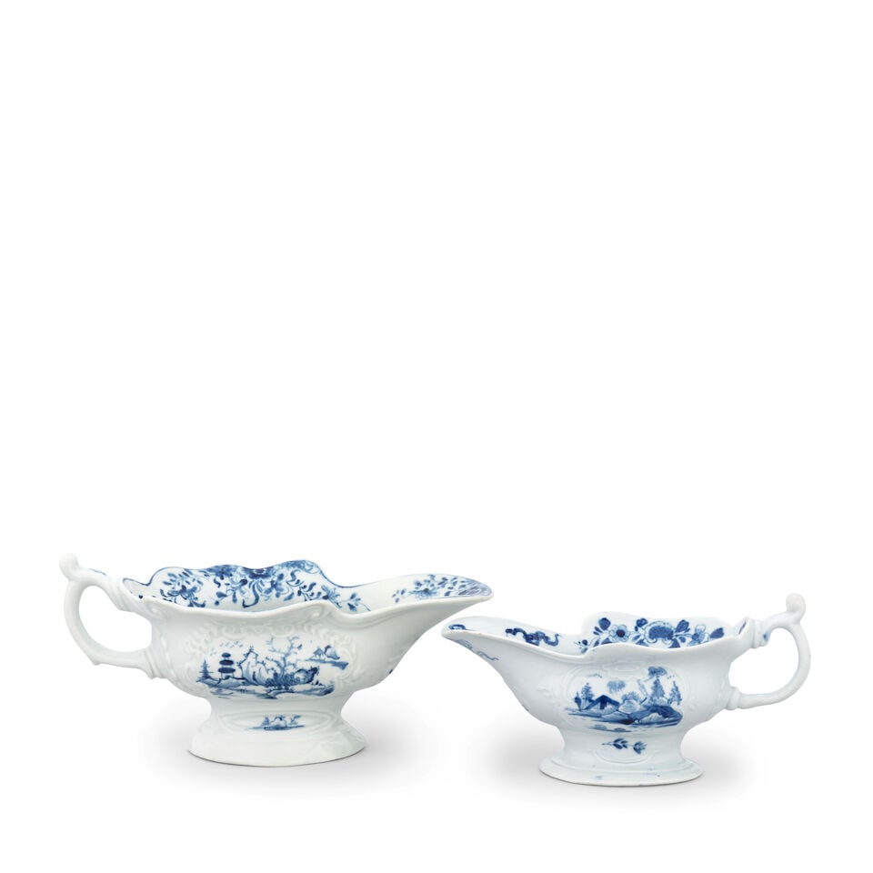Two rare Worcester sauceboats, circa 1753-55: Two rare Worcester sauceboats, circa 1753-55 Of high-footed form with a shaped rim, painted in blue, the smaller example with a version of the 'Crowded Island' pattern, 16.3cm long, workman's mark, th