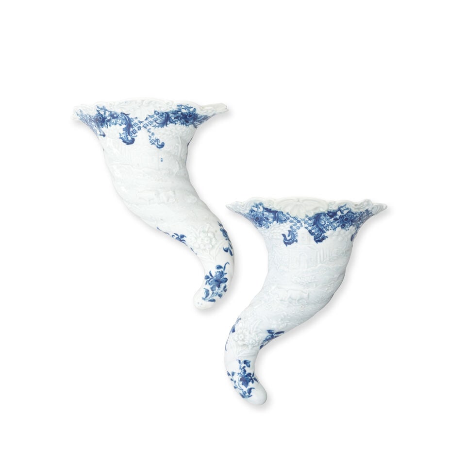 A pair of Worcester cornucopias, circa 1756-58: A pair of Worcester cornucopias, circa 1756-58 Of spiral horn shape with leafy scroll-moulded rims, crisply moulded in low relief with a rural landscape comprising a shepherd resting beneath a tree,
