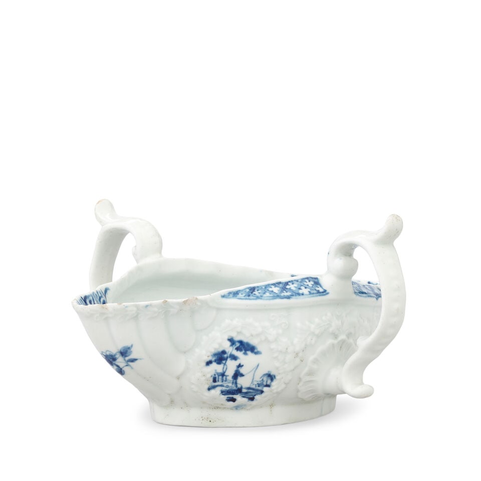 A rare Worcester double-lipped sauceboat, circa 1754-56: A rare Worcester double-lipped sauceboat, circa 1754-56 Twin handles with high scrolling thumbrests, the sides embossed with garlands of oak leaves, carefully painted in blue with the 'Fisherman with