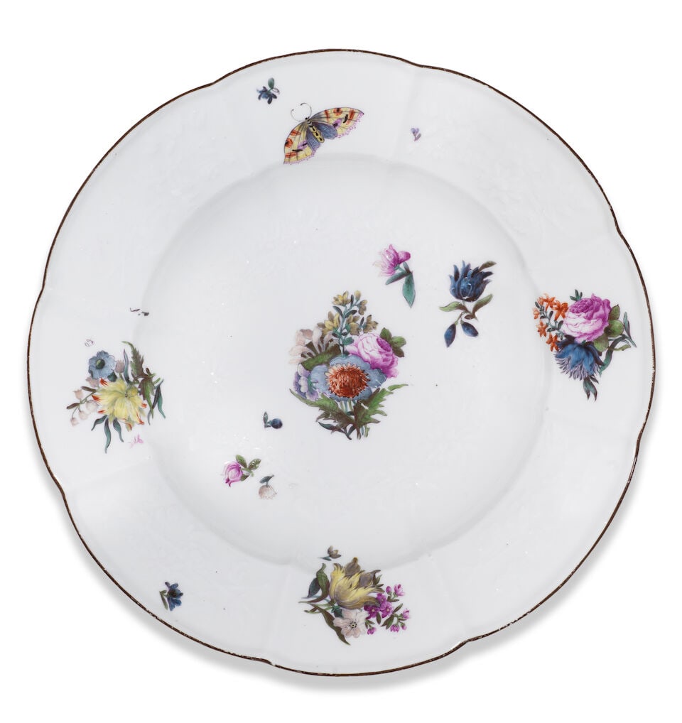 A Meissen deep plate, circa 1745: A Meissen deep plate, circa 1745 Moulded with the 'Gotzkowsky-Relief' pattern, modelled by J.F. Eberlein, painted with scattered Holzschnittblumen and a butterfly, brown-edged rim, 24cm diameter,