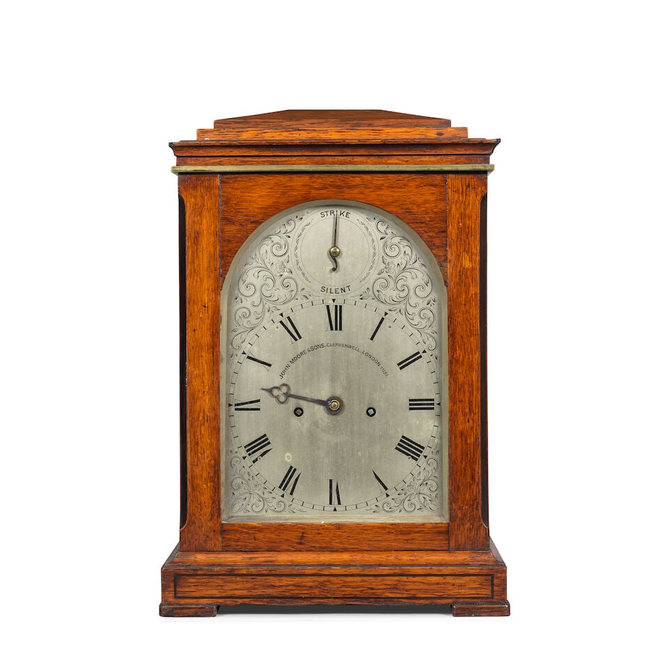 A late 19th century mahogany table clock John Moore & Sons, Clerkenwell, London number 11151: A late 19th century mahogany table clock John Moore & Sons, Clerkenwell, London number 11151 The case with sloped top over a brass moulded cornice to a plain front with fish scale sound frets to the