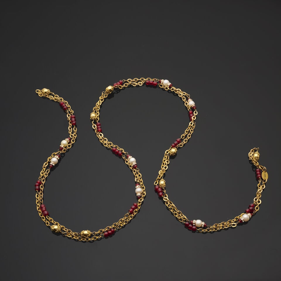 Chanel, circa 1983. Long sautoir chaine doré entrecoupée de perles rouges et perles d'...: Chanel, circa 1983. Long sautoir chaine doré entrecoupée de perles rouges et perles d'imitations chapeautées dorées et blanches. Chanel, circa 1983. Long gold-tone chain sautoir in
