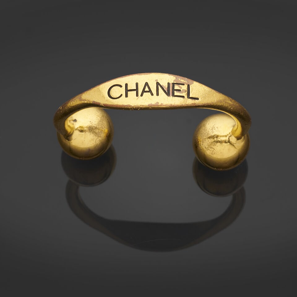 Chanel x Victoire de Castellane, collection Croisière 1992. Bracelet jonc en métal dor...: Chanel x Victoire de Castellane, collection Croisière 1992. Bracelet jonc en métal doré signé au nom de la Maison. Chanel x Victoire de Castellane, Cruise 1992 collection.
