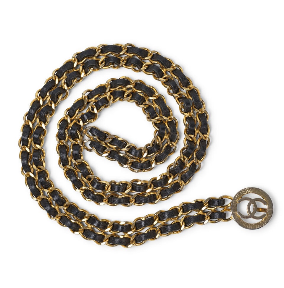 Chanel, années 1990. Ceinture double rang en métal doré entrelacée de cuir a...: Chanel, années 1990. Ceinture double rang en métal doré entrelacée de cuir agneau noir. Chanel, 1990s. Double-row belt in gold-tone metal interwoven with black lambskin leather. Fe