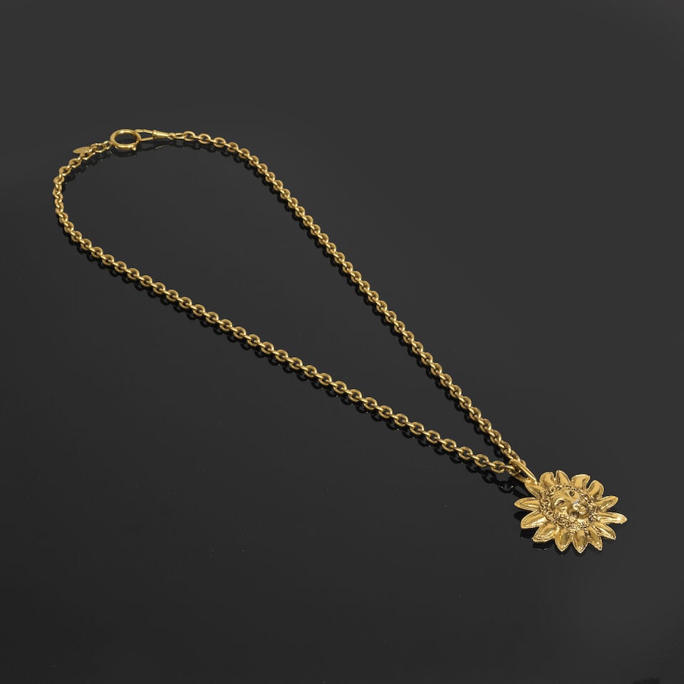 Chanel, années 1990. Sautoir chaine à pendentif Lion Soleil en métal doré. C...: Chanel, années 1990. Sautoir chaine à pendentif Lion Soleil en métal doré. Chanel, 1990s. Gold-tone metal sautoir chain necklace with a Sun Lion pendant. Directeur artistique: Karl