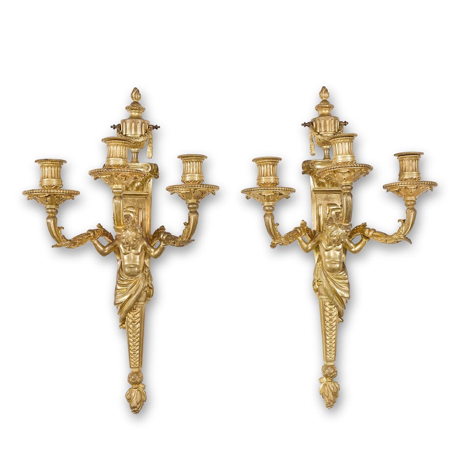 A pair of late 19th/early 20th century French gilt bronze three-light wall appliques In the Lou...: A pair of late 19th/early 20th century French gilt bronze three-light wall appliques In the Louis XVI style the acanthus scrolling arms with reeded nozzles and flared and fluted acanthus cast beaded c