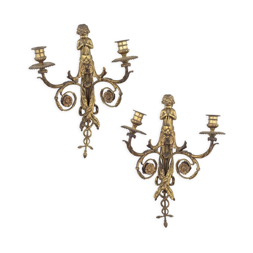 A pair of late 19th century French twin-light gilt bronze wall appliques In the Louis XVI style: A pair of late 19th century French twin-light gilt bronze wall appliques In the Louis XVI style The multi-scrolling foliate arms supporting stiff leaf candle nozzles with beaded edged drip pans