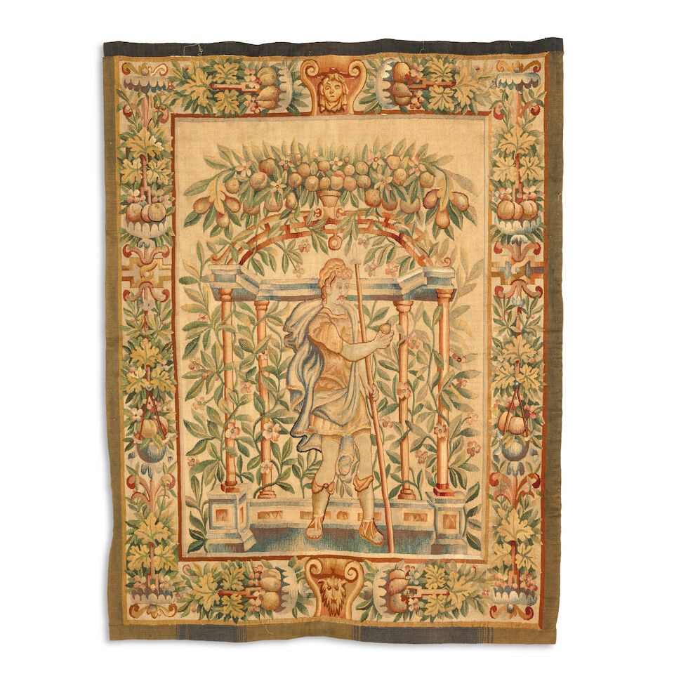 An 18th century tapestry panel Flemish or French: An 18th century tapestry panel Flemish or French Depicting a warrior picking fruit within a fruiting and foliate border, with suspension hoops, 156cm x 124cm For further information on this lot