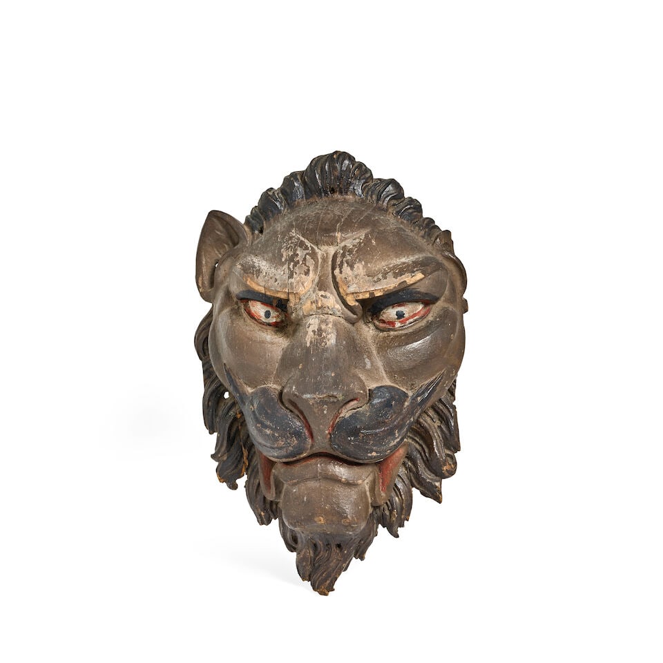 A early 19th century carved and polychrome mask head depicting a lion Possibly from a shop front: A early 19th century carved and polychrome mask head depicting a lion Possibly from a shop front The full face carved in relief with curling mane and moustache, 42cm high, 28cm wide, 15cm deep For