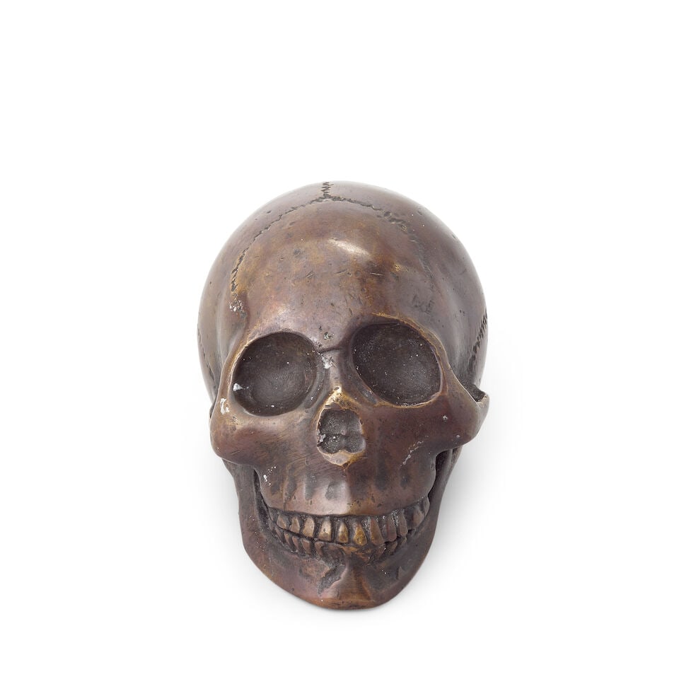 A North European patinated bronze memento mori Probably late 19th century: A North European patinated bronze memento mori Probably late 19th century Cast in the form of a human skull, 6.5cm high, 6cm wide, 9cm deep For further information on this lot please visit