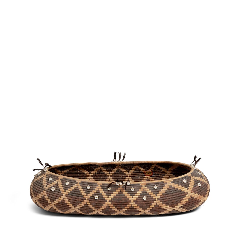 A Pomo oval negative basket: A Pomo oval negative basket Woven in a diamond latticework pattern, an attenuated zigzag encircling the base, disc beads and quail topknots as accents. dimensions 16 x 8 x 3