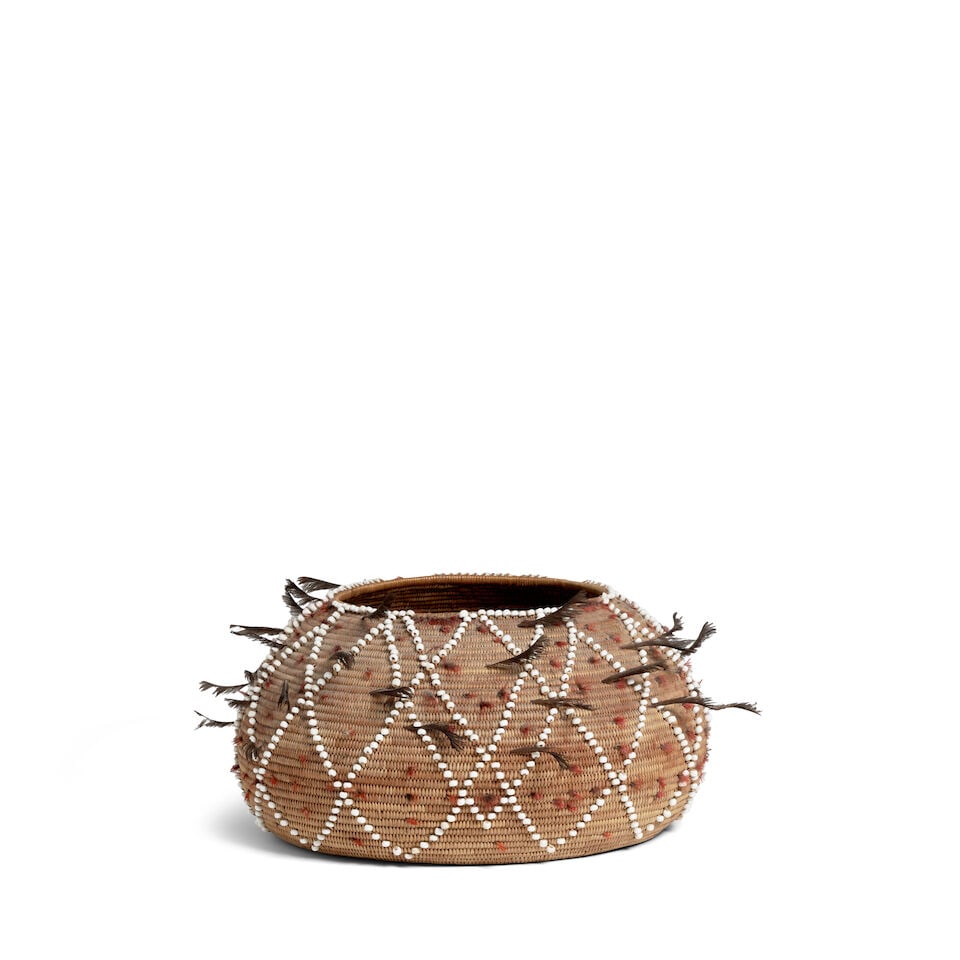 A Plains Miwok beaded basket: A Plains Miwok beaded basket The bowl decorated with a diamond lattice pattern of white pony beads woven into the body of the basket, quail topknots as accents. diameter 8 1/4in, height 4