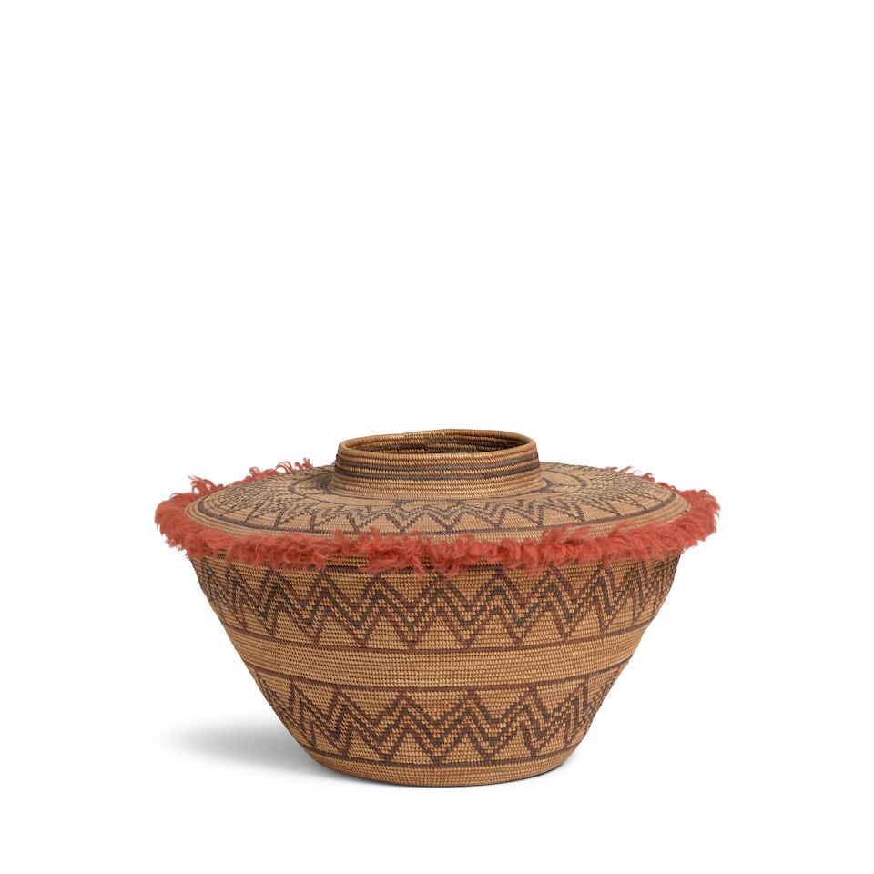 A Yokuts polychrome bottleneck basket: A Yokuts polychrome bottleneck basket Three bands of concentric zigzag patterns encircling the body and top, pairs of triangles at the base of the banded neck, yarn fringe about the