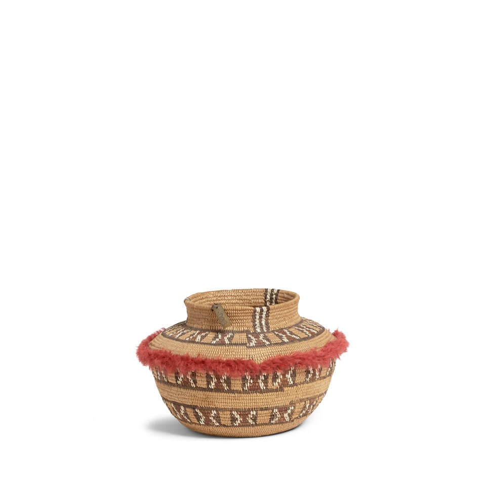 A Kawaiisu petite polychrome bottleneck basket: A Kawaiisu petite polychrome bottleneck basket Three bands of hourglass motifs about the body, yarn fringe encircling the shoulder, a chainlink band at the base, with unidentified metal collection