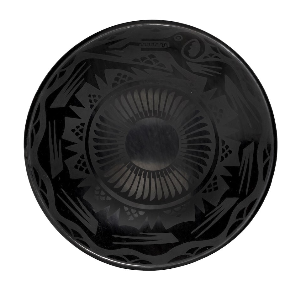 A Crucita Calabaza (Blue Corn) blackware plate: Crucita Calabaza (Blue Corn) San Ildefonso, (1921-1999), a blackware plate, a 10-humped avanyu encircling the outer edge, rain clouds as accents, a repeat feather design about the center, signed