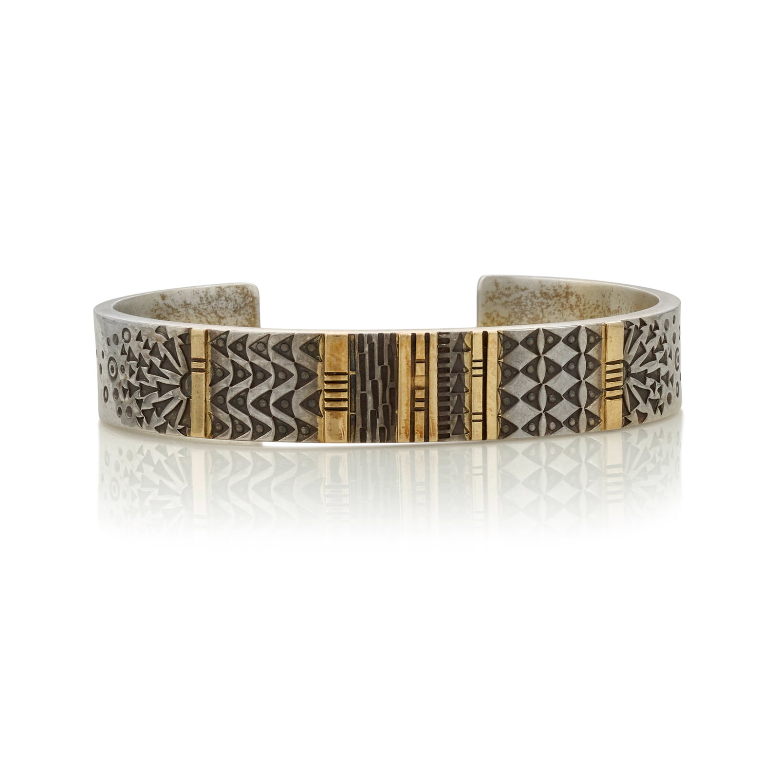 A Norbert Peshlakai silver and gold cuff bracelet: Norbert Peshlakai Diné (Navajo), (b. 1953), a silver and gold cuff bracelet, panels of finely-stamped motifs framed by gold spacers, the artist's maker's mark stamped adjacent to one terminal. in