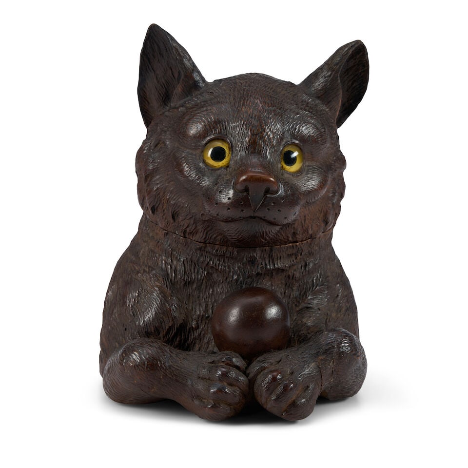 An Austrian or German Black Forest Cat Tobacco Jar late 19th/early 20th century: An Austrian or German Black Forest Cat Tobacco Jar late 19th/early 20th century Modeled as the upper half of a cat playing with a ball, the hinged head inset with glass eyes and opening to a hollowed 