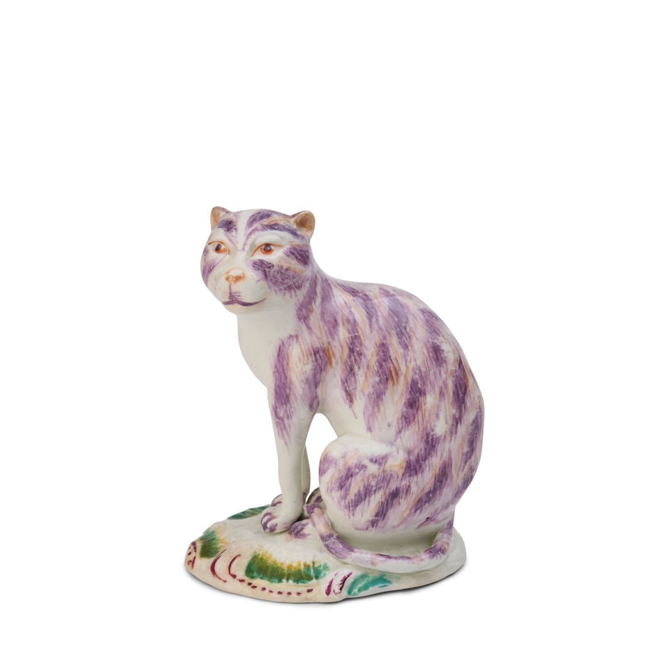 A Derby Porcelain Model of a Seated Cat circa 1760: A Derby Porcelain Model of a Seated Cat circa 1760 Its striped fur marked in shades of puce and brown, set on a scroll-edged base picked out in puce and green. height 4 in. (10.16 cm.); width 3 1/2 in