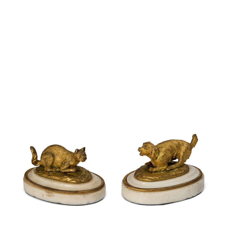 A Pair of Gilt Bronze Paperweight Models of a Cat and a Dog French, late 18th/early 19th century: A Pair of Gilt Bronze Paperweight Models of a Cat and a Dog French, late 18th/early 19th century Each on a stepped marble base with gilt bronze twisted edging. each height 3 in. (7.62 cm.); width 4 1/