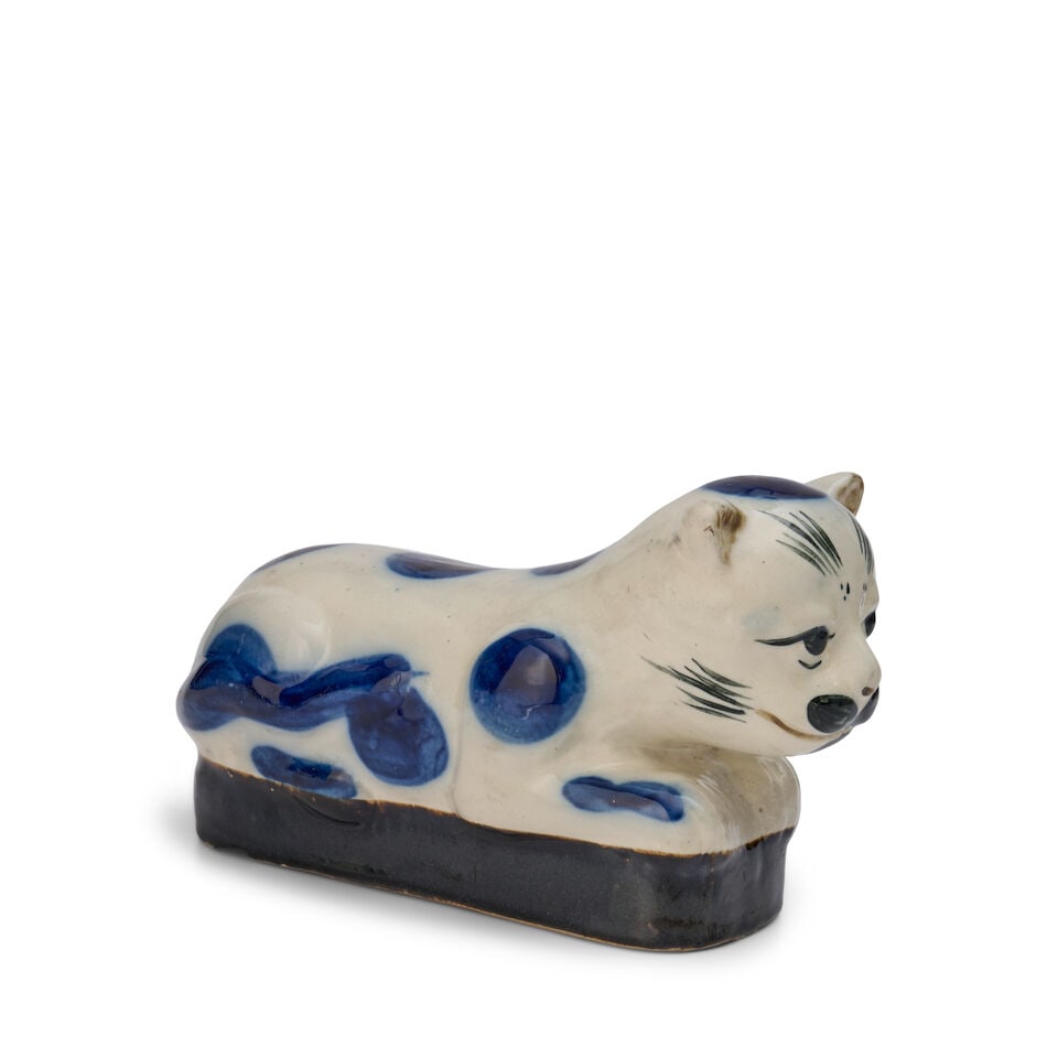 A Blue and White Porcelain Cat-form Pillow China, Qing dynasty, late 19th century: A Blue and White Porcelain Cat-form Pillow China, Qing dynasty, late 19th century Decorated with blue spots and whisker and fur details. height 7 in. (17.8 cm.); width 11 in. (27.9 cm.); depth 3 3/4 i