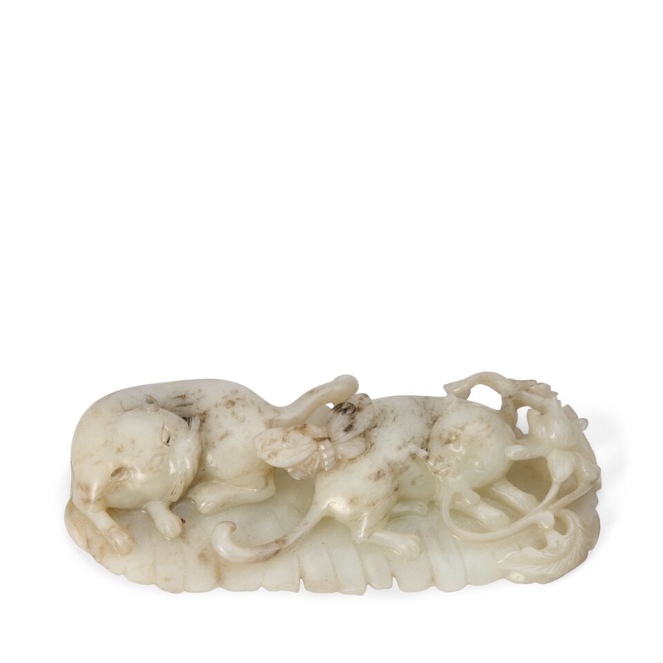 A White and Brown Jade Carving of Two Cats China, Qing Dynasty, 18th/19th century: A White and Brown Jade Carving of Two Cats China, Qing Dynasty, 18th/19th century The two cats in recumbent pose on a banana leaf with a butterfly between them, one cat playfully holding a lotus stem 
