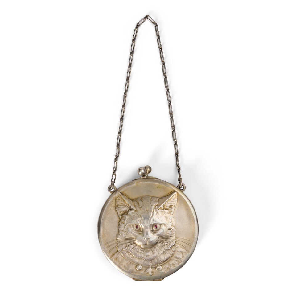 A Silver-gilt Cat Compact early 20th century, 800 standard: A Silver-gilt Cat Compact early 20th century, 800 standard Circular, embossed with a cat's head to each side, red stone eyes, the interior with two hinged compartments to one side and a mirror to the 