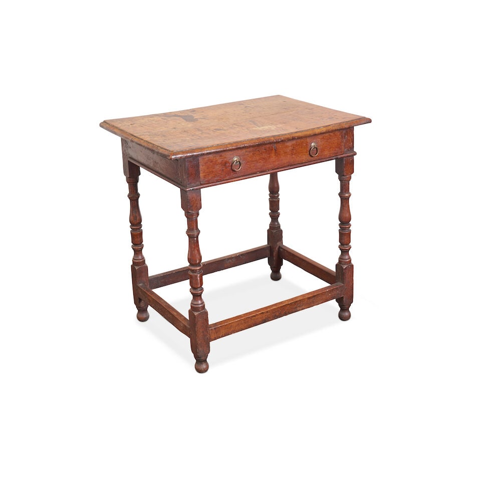 An English oak side table, early 18th century,: An English oak side table, early 18th century, with a well figured rectangular moulded oak top, above a single frieze drawer, with brass drop ring handles, raised on turned legs with peripheral