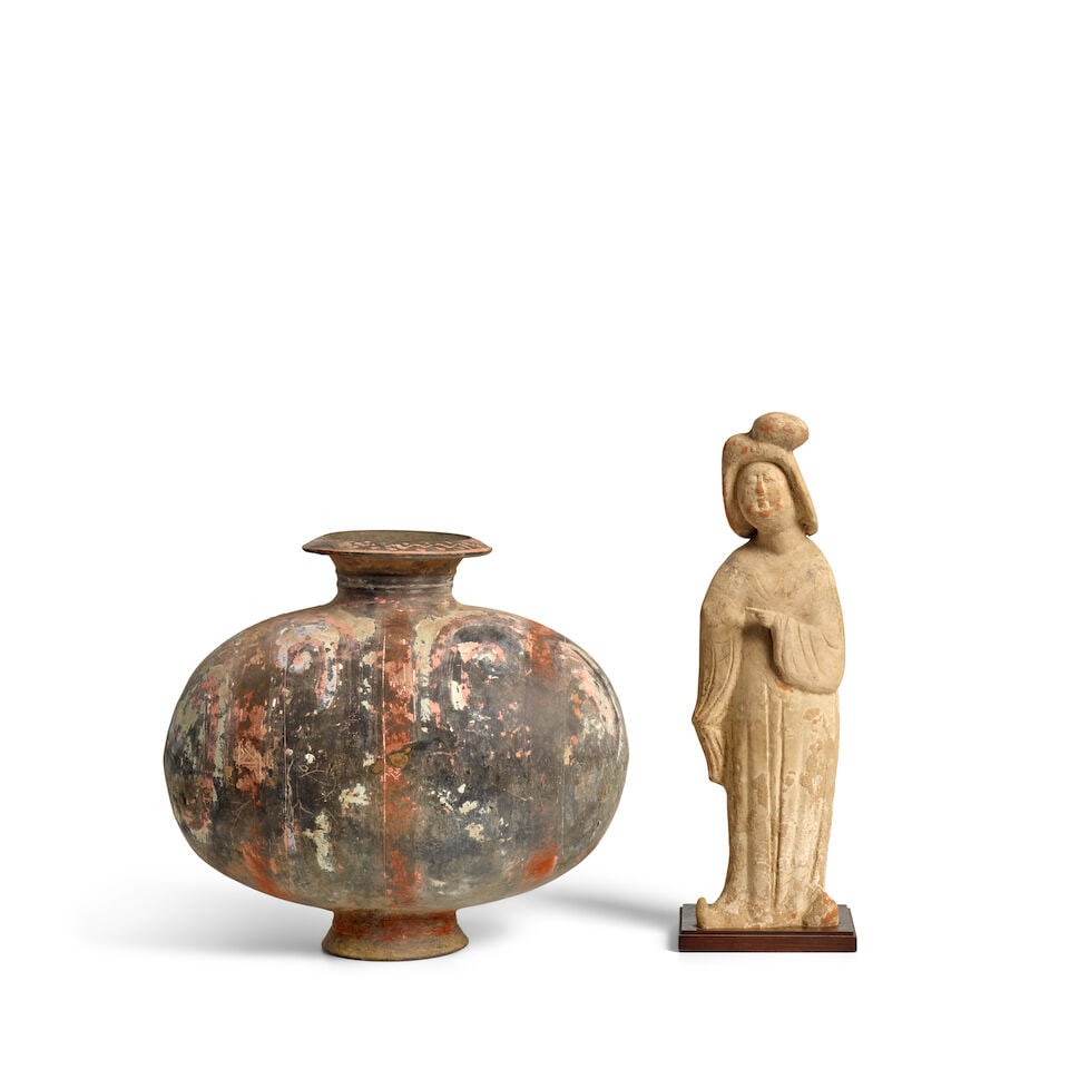 A PAINTED POTTERY ATTENDANT AND A PAINTED POTTERY 'COCOON' JAR Han Dynasty (2): A PAINTED POTTERY ATTENDANT AND A PAINTED POTTERY 'COCOON' JAR Han Dynasty The figure: 14 1/2in (36.8 cm), wood stand; the jar:11 3/4in (30cm) (2). Footnotes: 漢 彩繪陶女