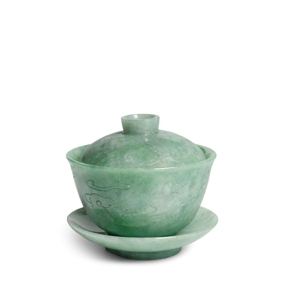 A JADEITE CUP SET 20th century (3): A JADEITE CUP SET 20th century Comprising a cup, cover, and a stand, all incised with swirling cloud decorations. 3 7/16in (8.7cm) diam of stand; 3 3/8in (8.5cm) diam of
