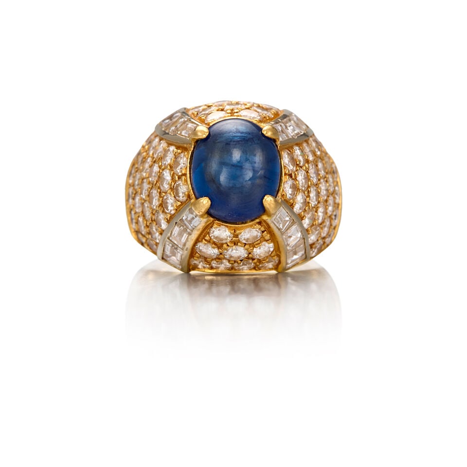 AN 18K GOLD, SAPPHIRE AND DIAMOND RING: AN 18K GOLD, SAPPHIRE AND DIAMOND RING • One oval cabochon sapphire weighing approximately 3.11 carats total • Twelve baguette diamonds weighing approximately 0.84 carat total •