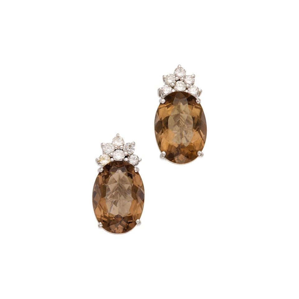 18K WHITE GOLD, SMOKY QUARTZ AND DIAMOND EARRINGS: 18K WHITE GOLD, SMOKY QUARTZ AND DIAMOND EARRINGS • Two oval shaped smoky quartz weighing approximately 12.58 carats total • Twelve round brilliant cut diamonds weighing approximately
