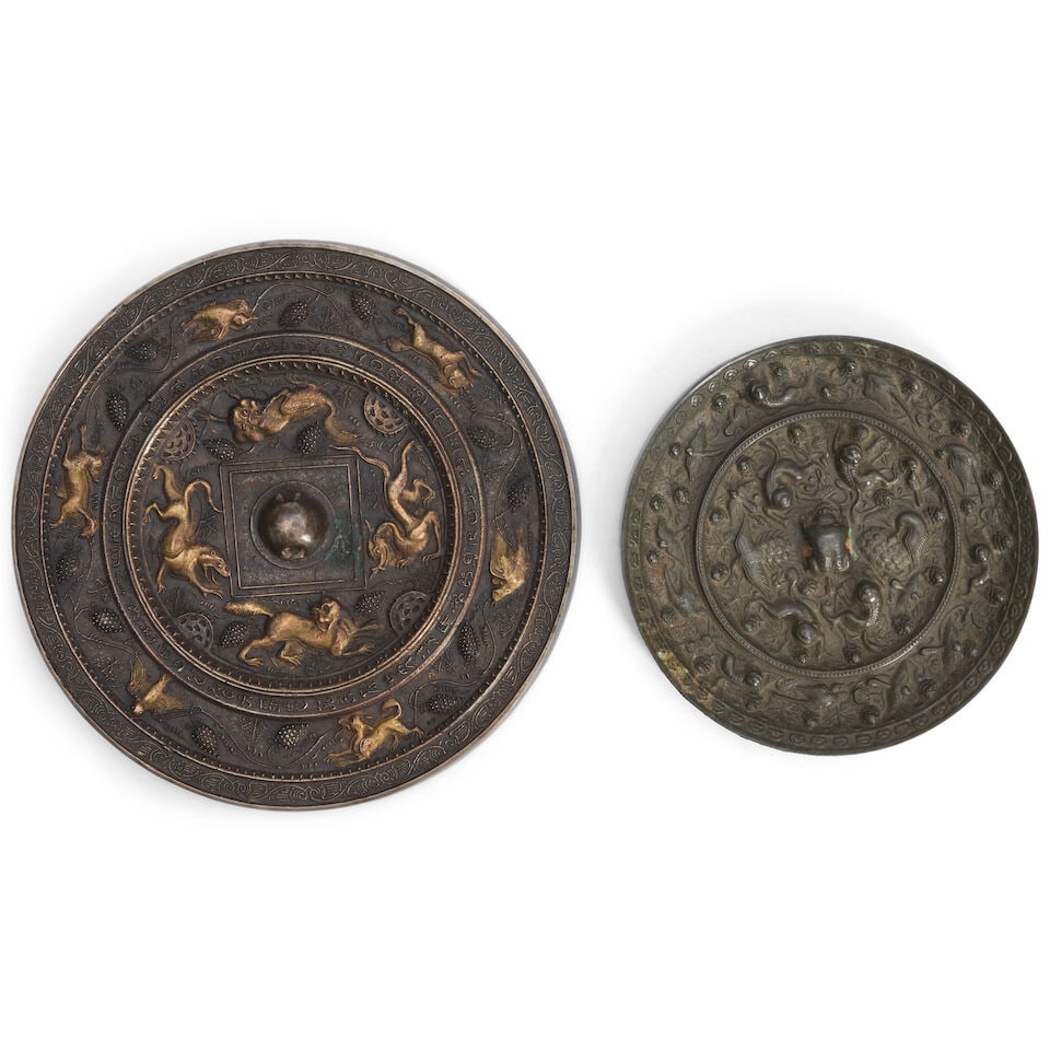 Two Bronze Mirrors China, 20th century, (2): Two Bronze Mirrors China, 20th century, both round, the first Tang style with 'lion and grape' motif; the second Han style with lions, peacocks, and birds 6 1/2in (16.5cm) and 7 1.4（22.5cmʌ