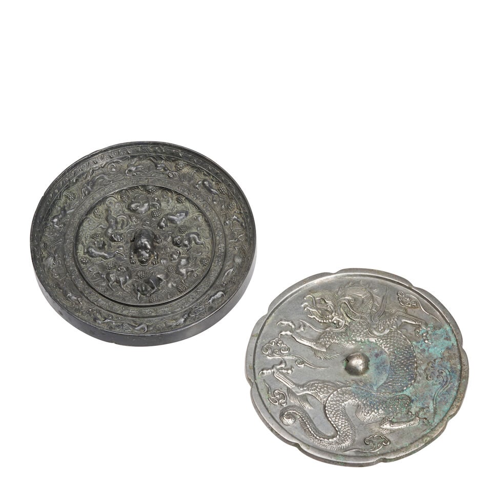 Two Bronze Mirrors China, Tang dynasty style, 20th century, (2): Two Bronze Mirrors China, Tang dynasty style, 20th century, One round with 'lion and grapevine' motif; the other with a foliate rim and dragon decoration 8in(20.4cm) diam. each (2). Footnotes: Provena