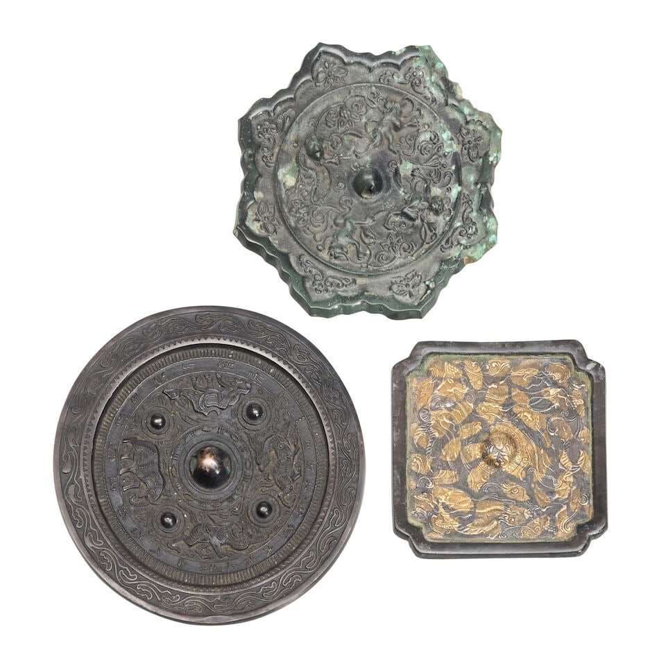 Three Bronze Mirrors China, Han and Tang dynasty style, 20th century, (3): Three Bronze Mirrors China, Han and Tang dynasty style, 20th century, A round mirror with animal motifs; a foliate rimmed mirror with lions; and a square mirror with mythical figures and gilt patches 