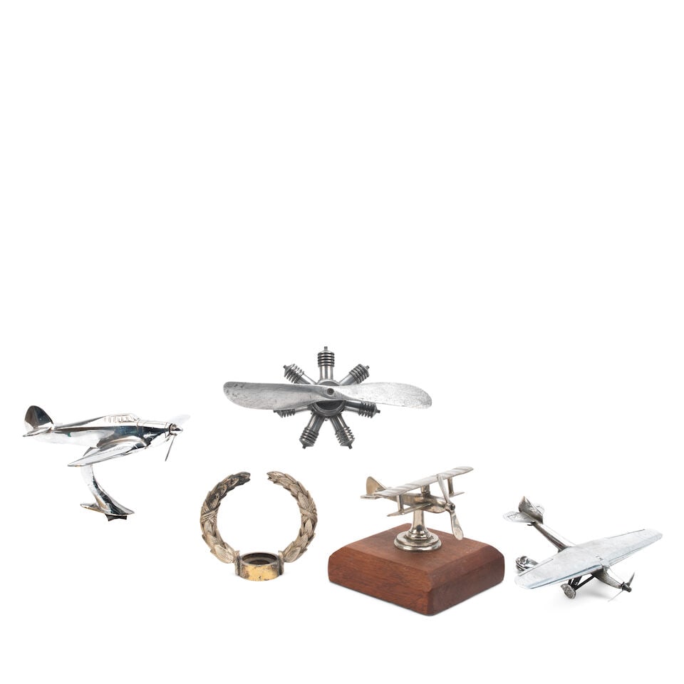 Four aviation mascots, ((5)): Four aviation mascots, comprising a post-War chrome-plated Hawker Hurricane by Louis Lejeune, wingspan 18cm (two propeller blades missing); a chrome-plated high-wing monoplane, wingspan 20cm; a