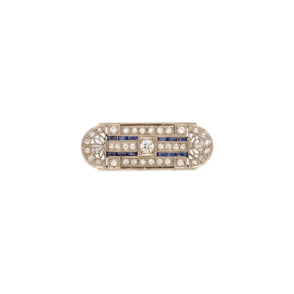 AN ANTIQUE PLATINUM, DIAMOND AND SYNTHETIC SAPPHIRE BROOCH: AN ANTIQUE PLATINUM, DIAMOND AND SYNTHETIC SAPPHIRE BROOCH • One round brilliant-cut, numerous old mine-cut and old European-cut diamonds weighing approximately 0.92 carat total • Twelve