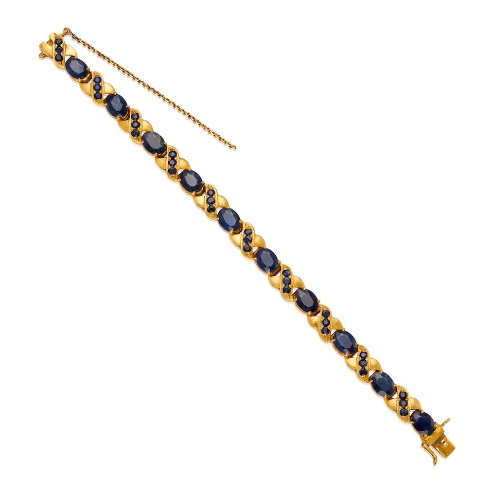 A GOLD, SAPPHIRE AND LATTICE DIFFUSION SAPPHIRE BRACELET: A GOLD, SAPPHIRE AND LATTICE DIFFUSION SAPPHIRE BRACELET • 11K gold bracelet with low karat safety chain • Ten oval-shaped sapphires weighing approximately 10.90 carats total •